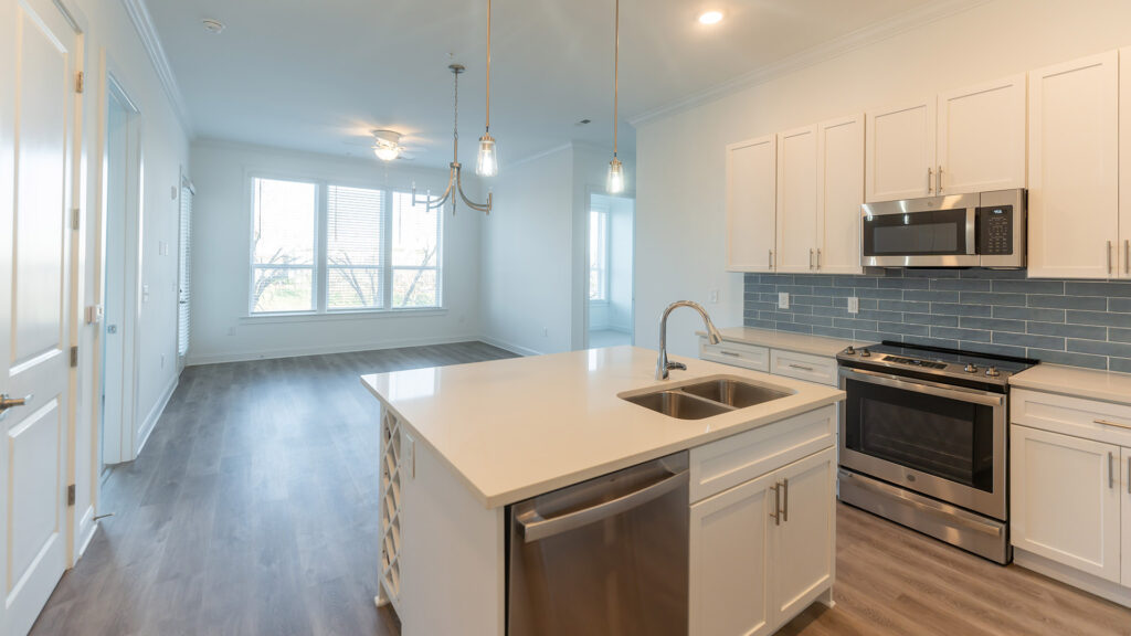 Kitchen at Cameryn Elise, luxury apartments for seniors, with blue colored tile backsplash, chandelier, kitchen island, stainless appliances